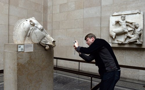 Turista tira fotos de estátua do Partenon no Museu Britânico.